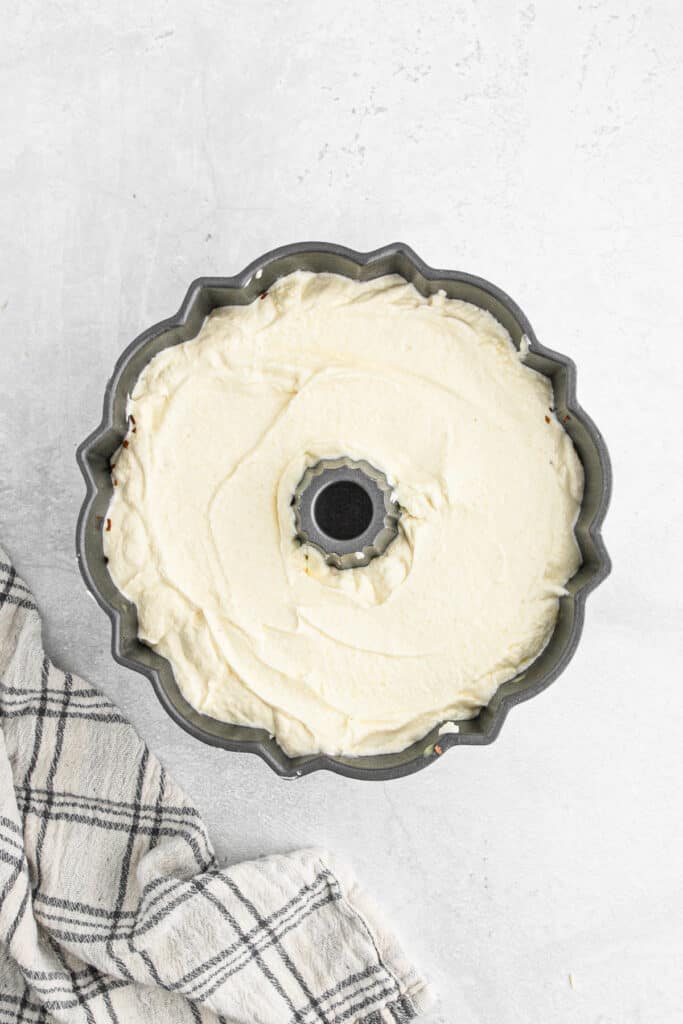 Cake batter placed on top of the sliced almonds in the bundt pan.