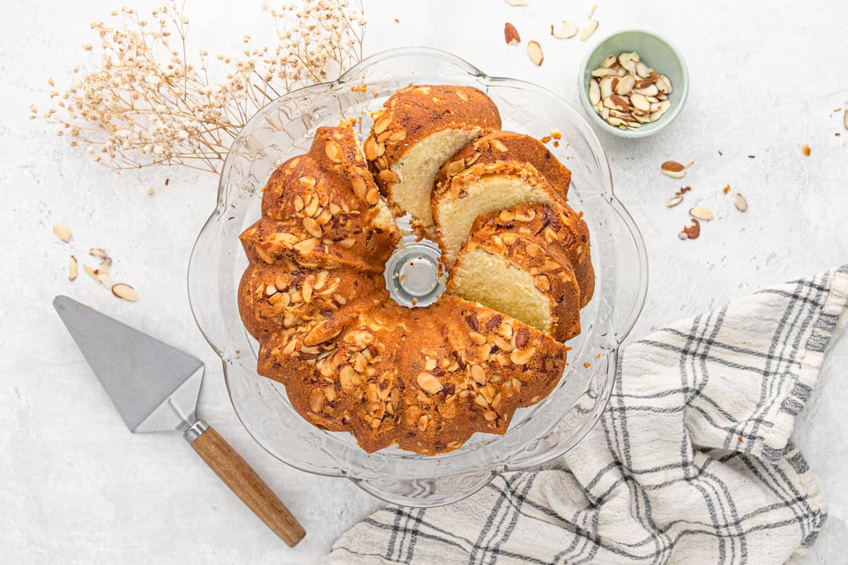 Almond pound cake on a cake stand with a few slices cut.