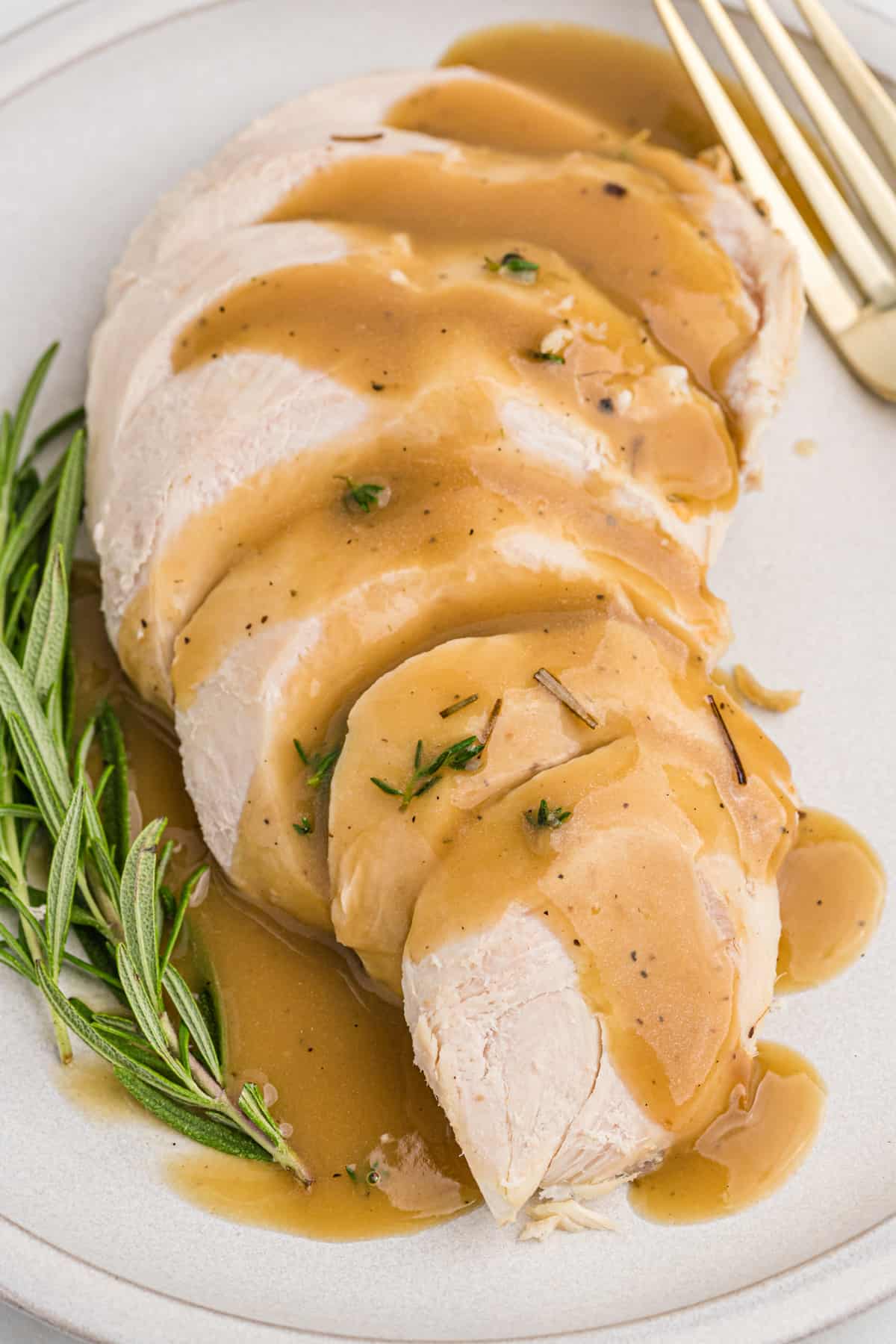 Homemade turkey gravy poured over turkey breast slices on a white platter.