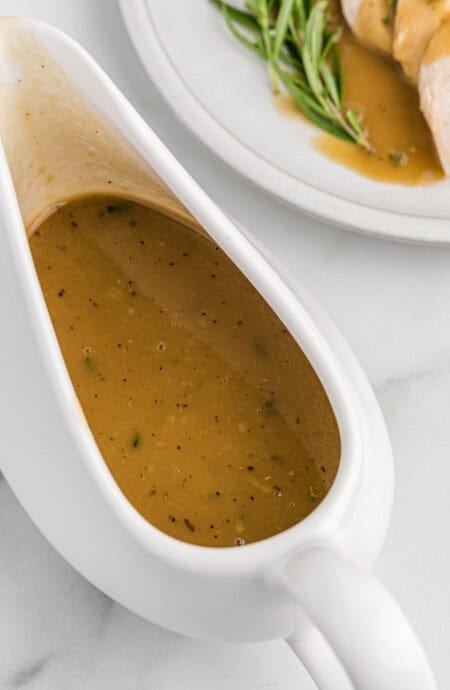 Homemade turkey gravy in a white ceramic gravy boat.