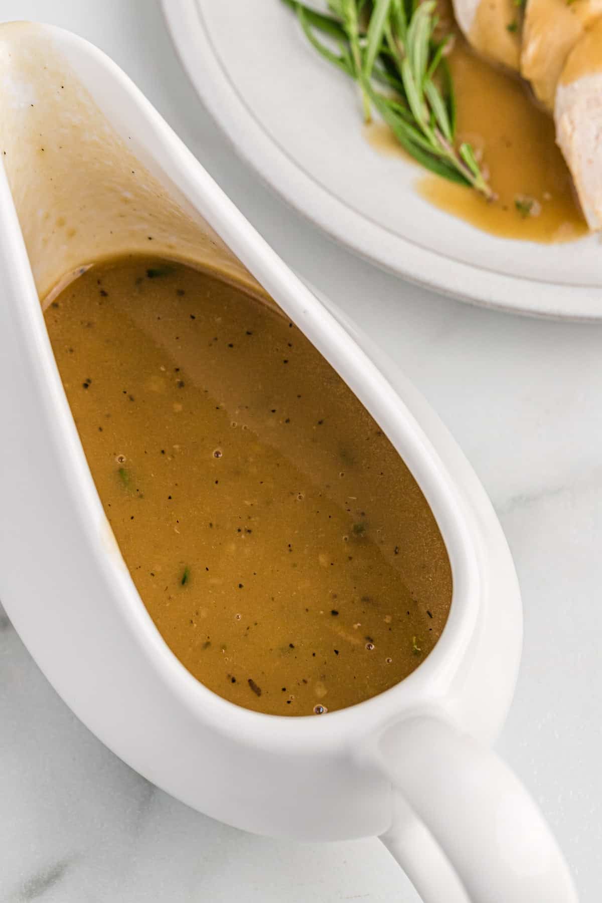 Homemade turkey gravy in a white ceramic gravy boat.