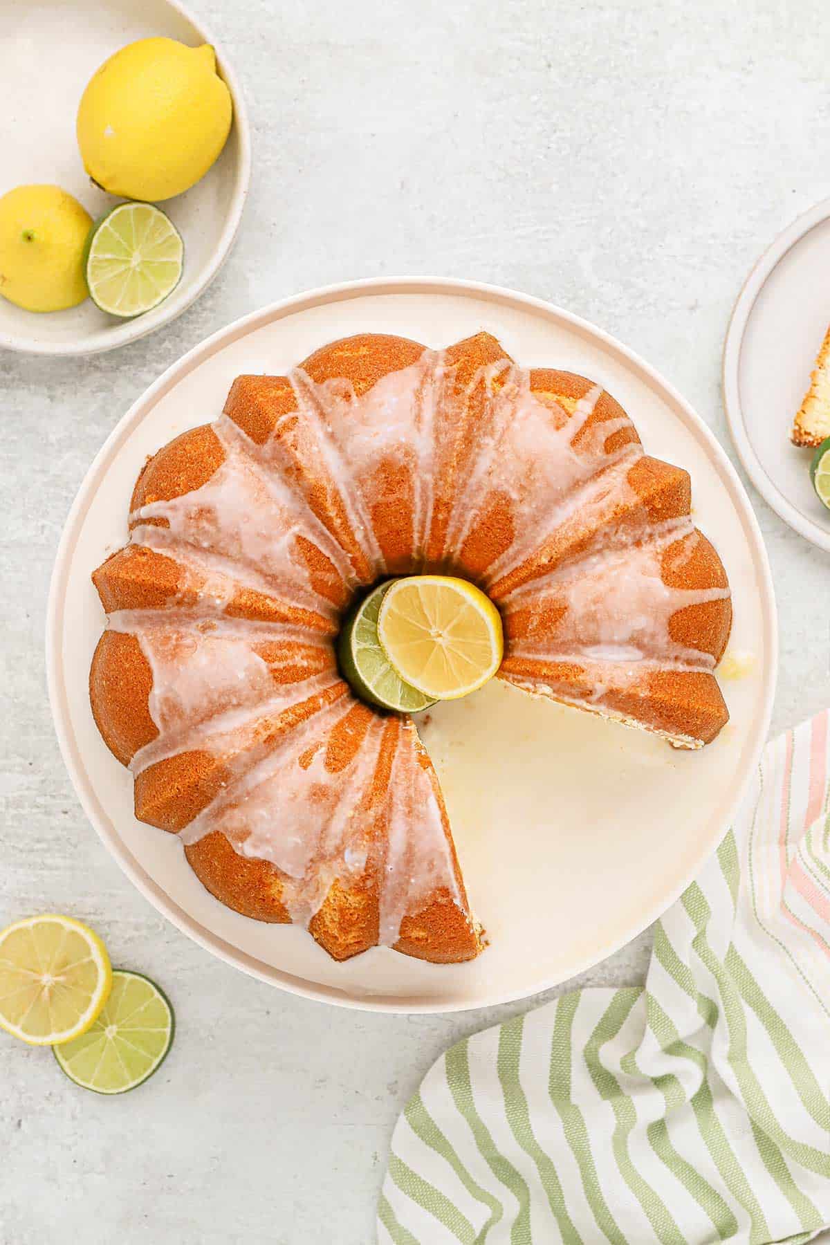 7 up pound cake 7 up pound cake recipe with a slice missing.on a white background with lemons and limes on a white plate