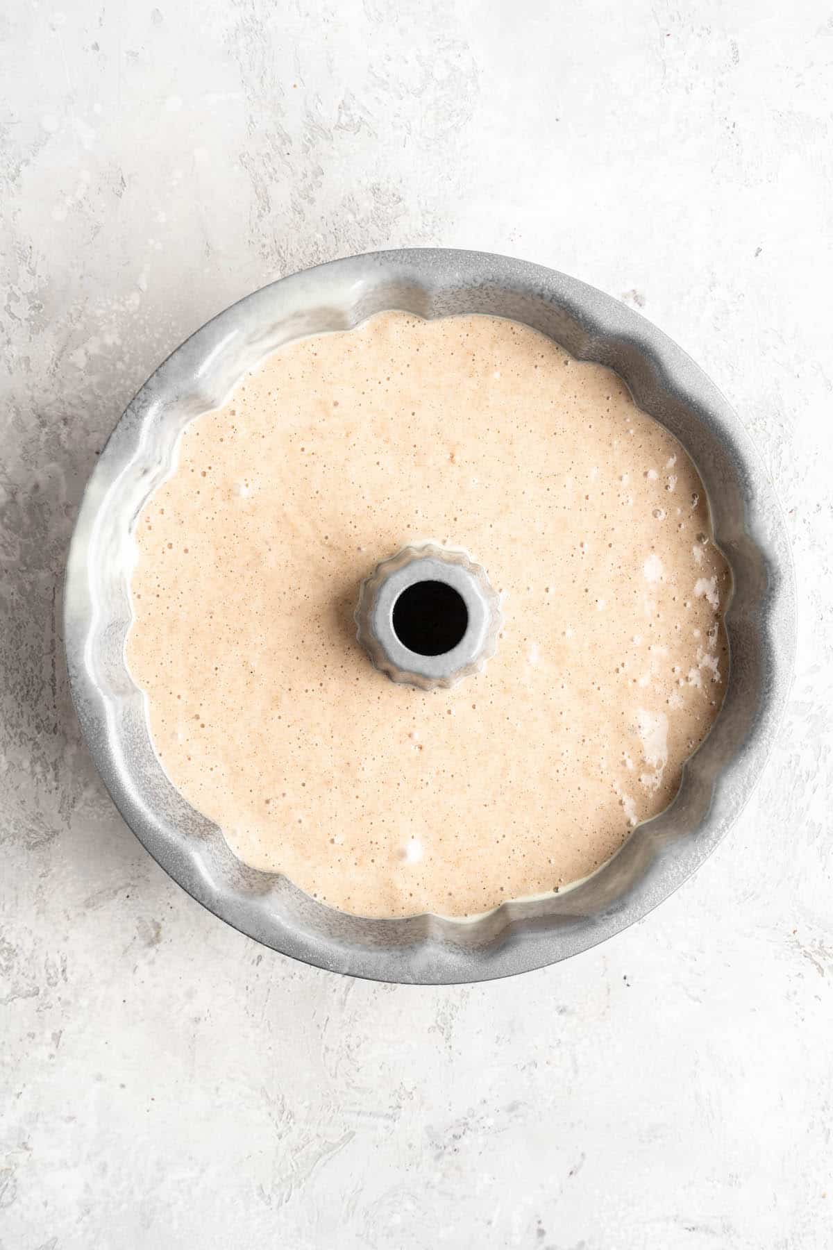 Batter in a bundt pan before baking on a white countertop
