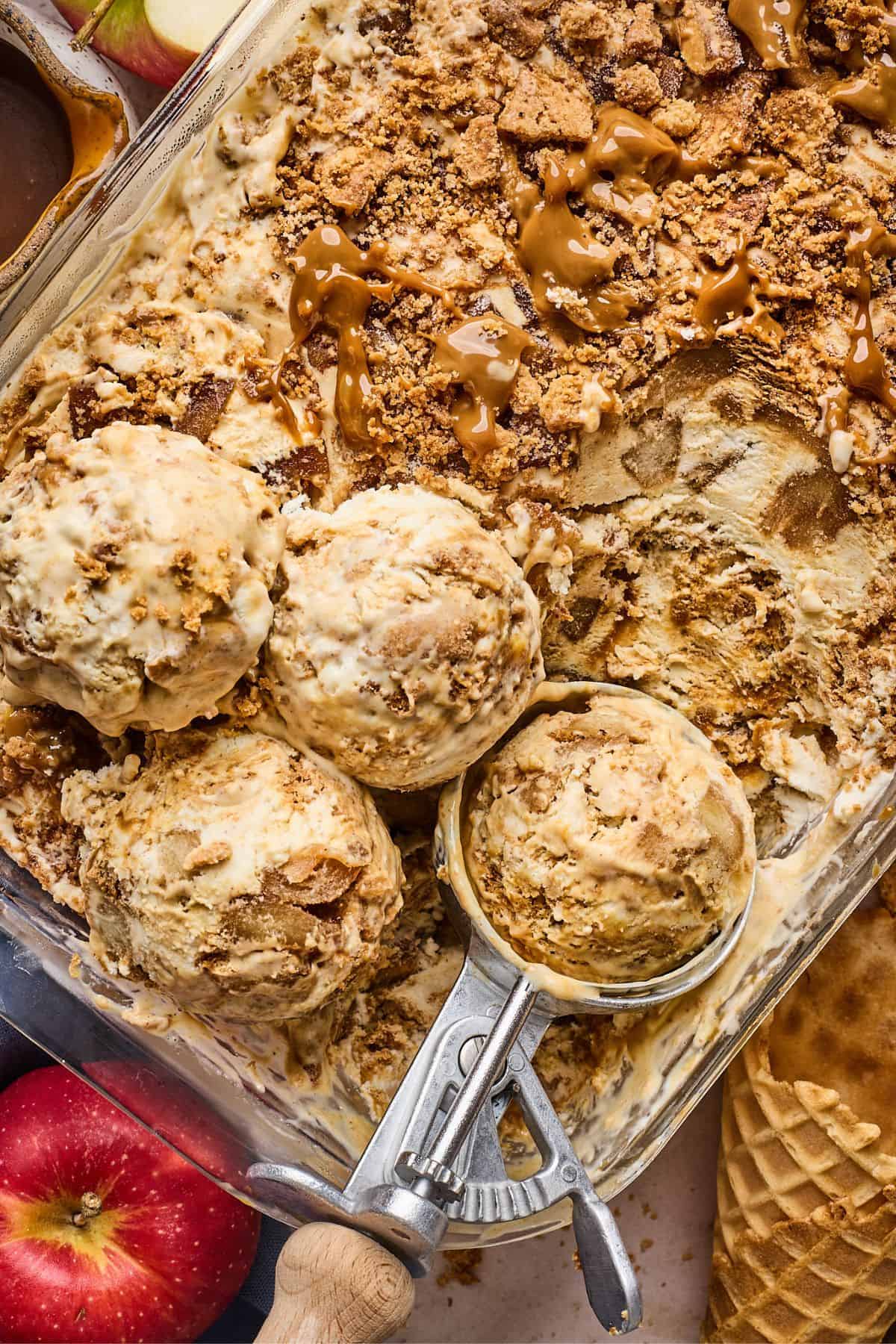 Scoops of apple pie ice cream with an ice cream scoop in the container it was frozen in