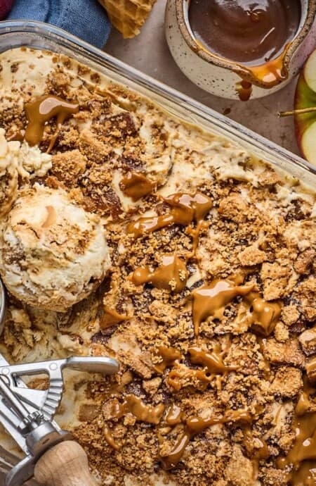 Scoops of apple pie ice cream with an ice cream scoop in the container it was frozen in