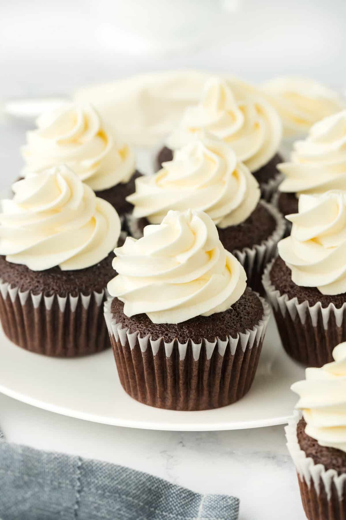 Homemade chocolate cupcakes on a white plate with american frosting in a white background