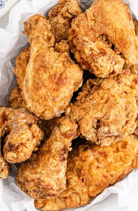 A serving bowl lined with a paper towel and filled with big mama's fried chicken on the table.