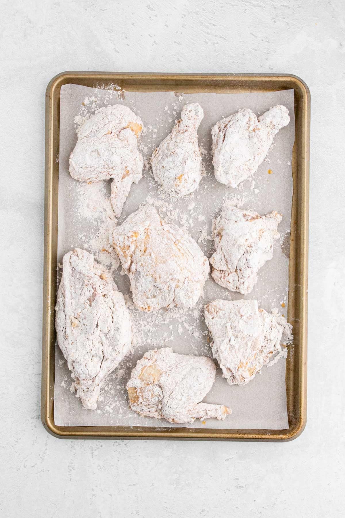 Breaded chicken laid out on a baking sheet before cooking.