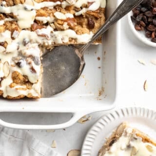 Bread pudding in a baking dish with a slice removed to a plate.