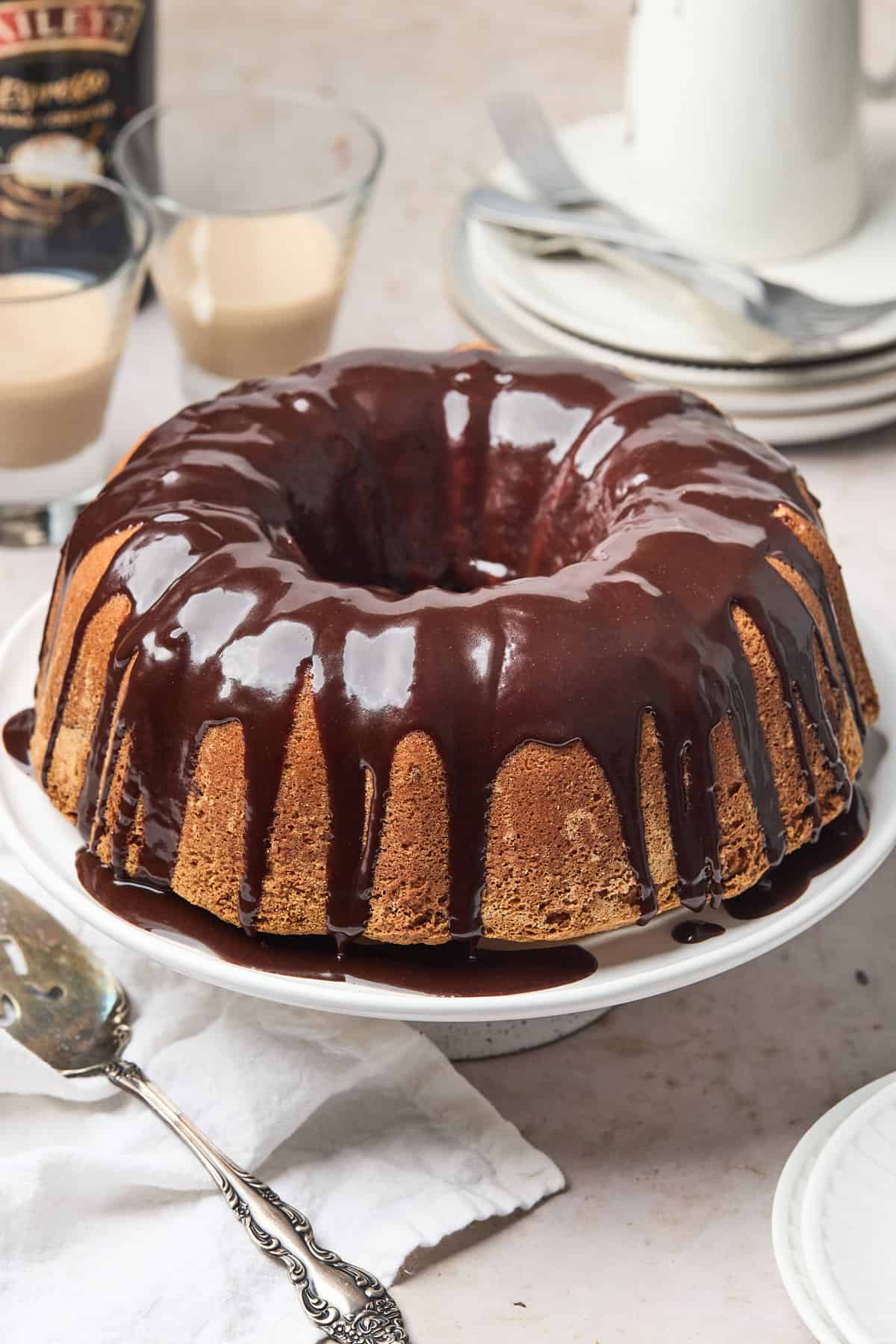 Swirl cake topped with chocolate glaze on the table with glasses of bailey's in the background.