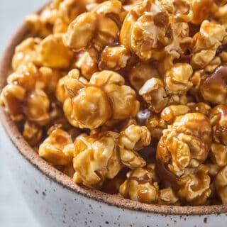 A close up of caramel corn in a gray speckled bowl ready to devour