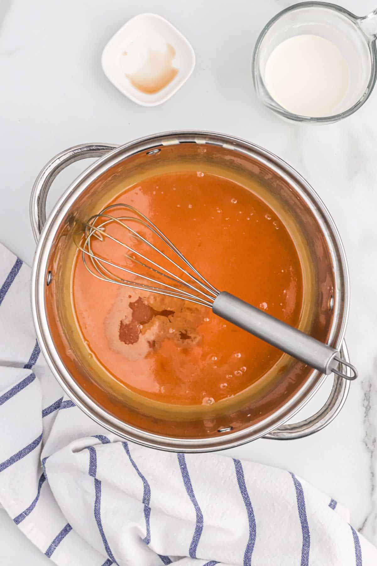 easy caramel sauce Caramel sauce cooking in a pot with a whisk.