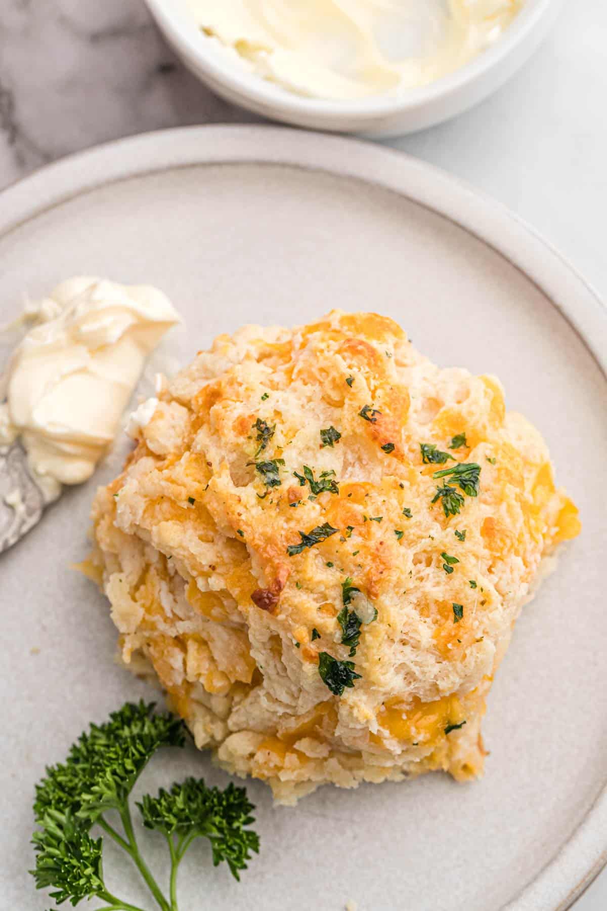A baked cheddar cheese biscuit on a plate with butter.