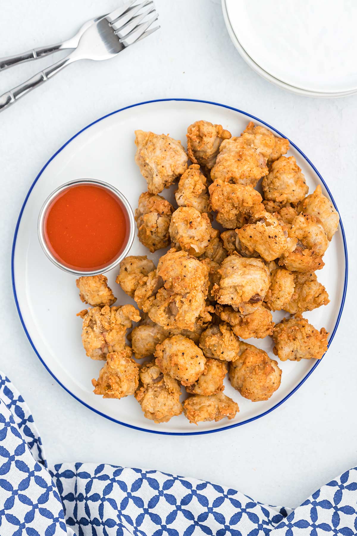 Overhead view of chicken gizzards on a white plate with buffalo sauce.