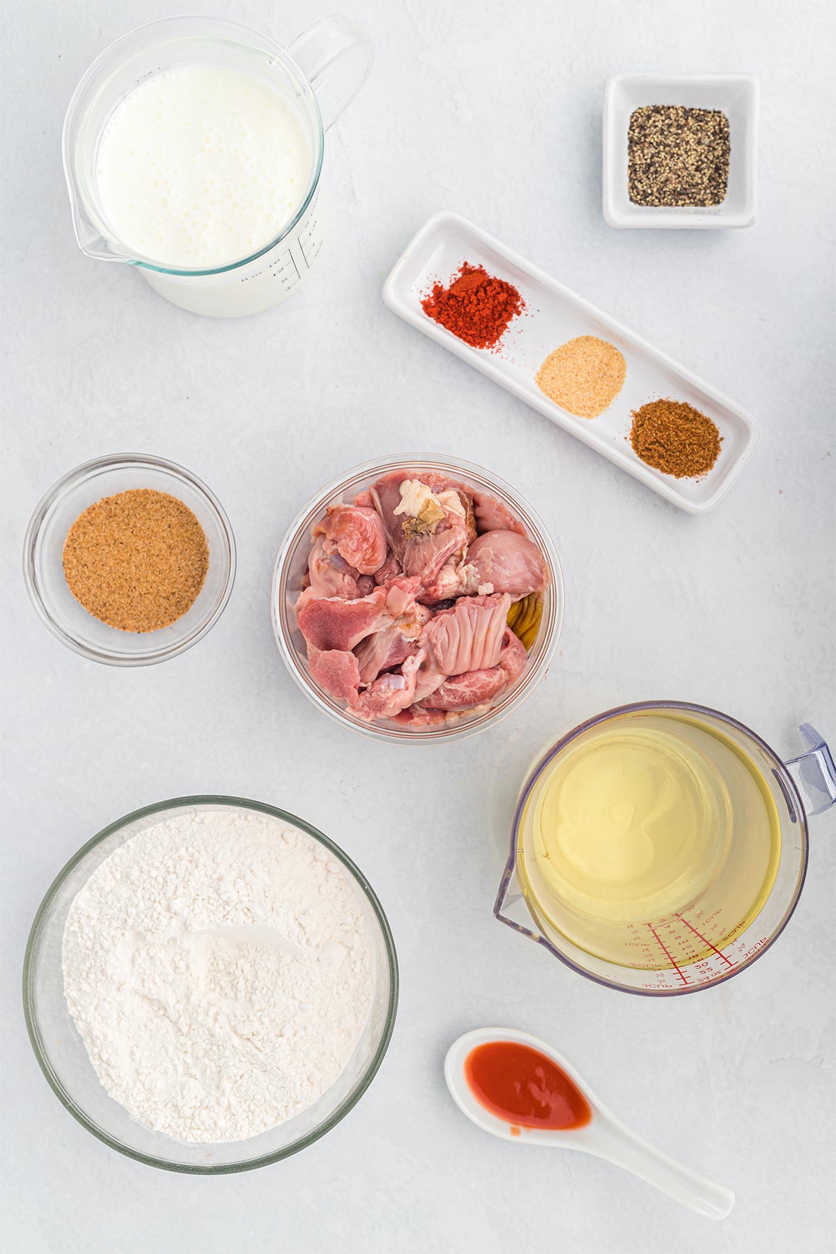 Ingredients to make southern fried chicken gizzards on a white countertop in glass bowls.