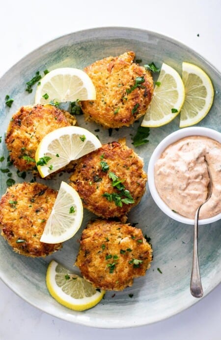 Gorgeous crab cakes scattered with lemon wedges and remoulade sauce ready to serve