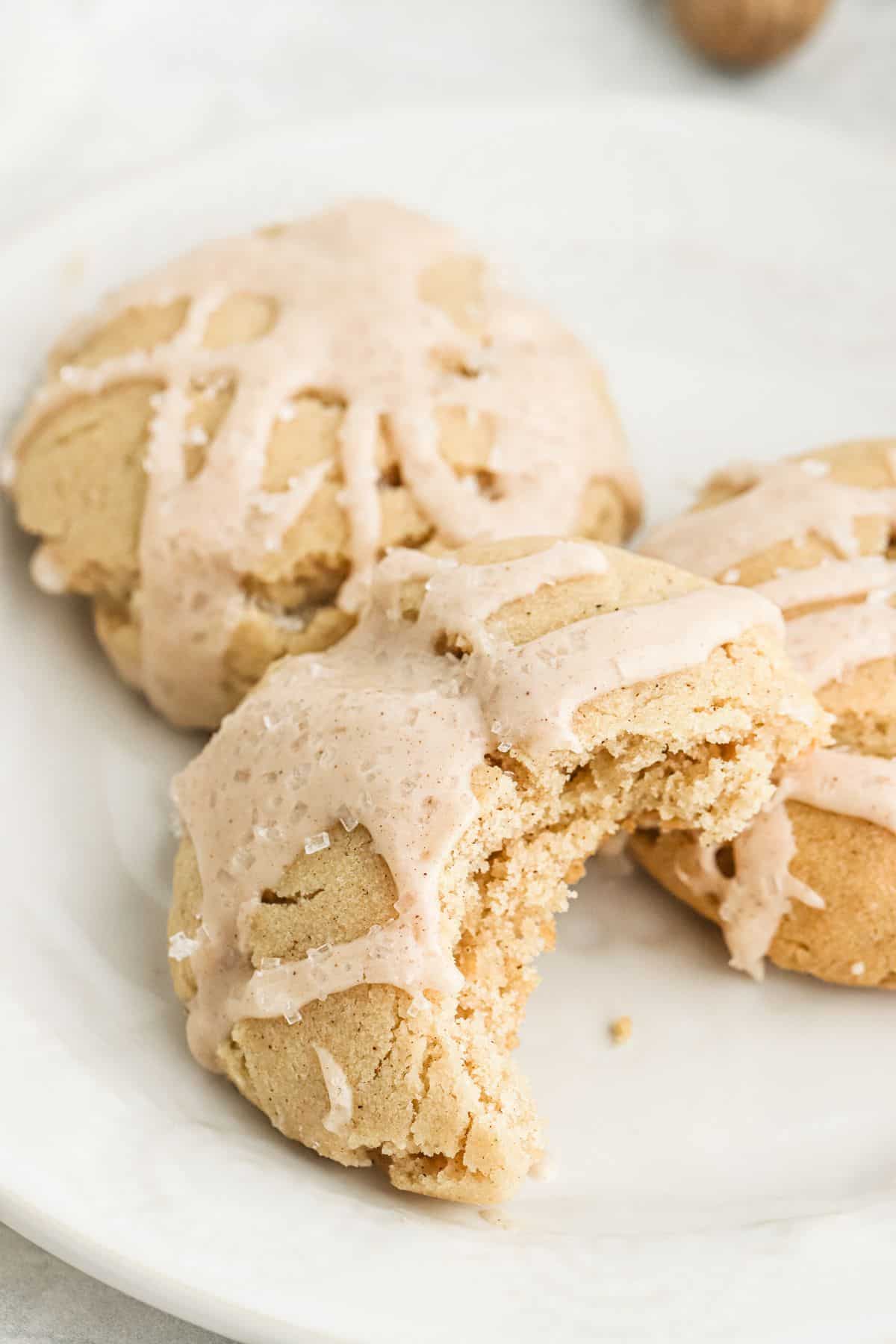 Eggnog Iced Butter Cookies | Grandbaby Cakes Three eggnog cookies on a plate with a bite missing from one.