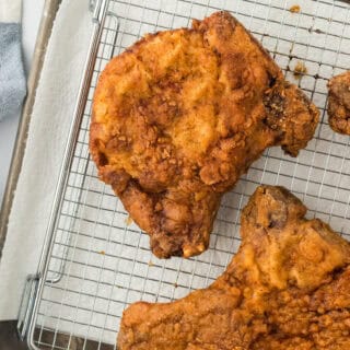 pan fried pork chops on a wire rack draining after frying