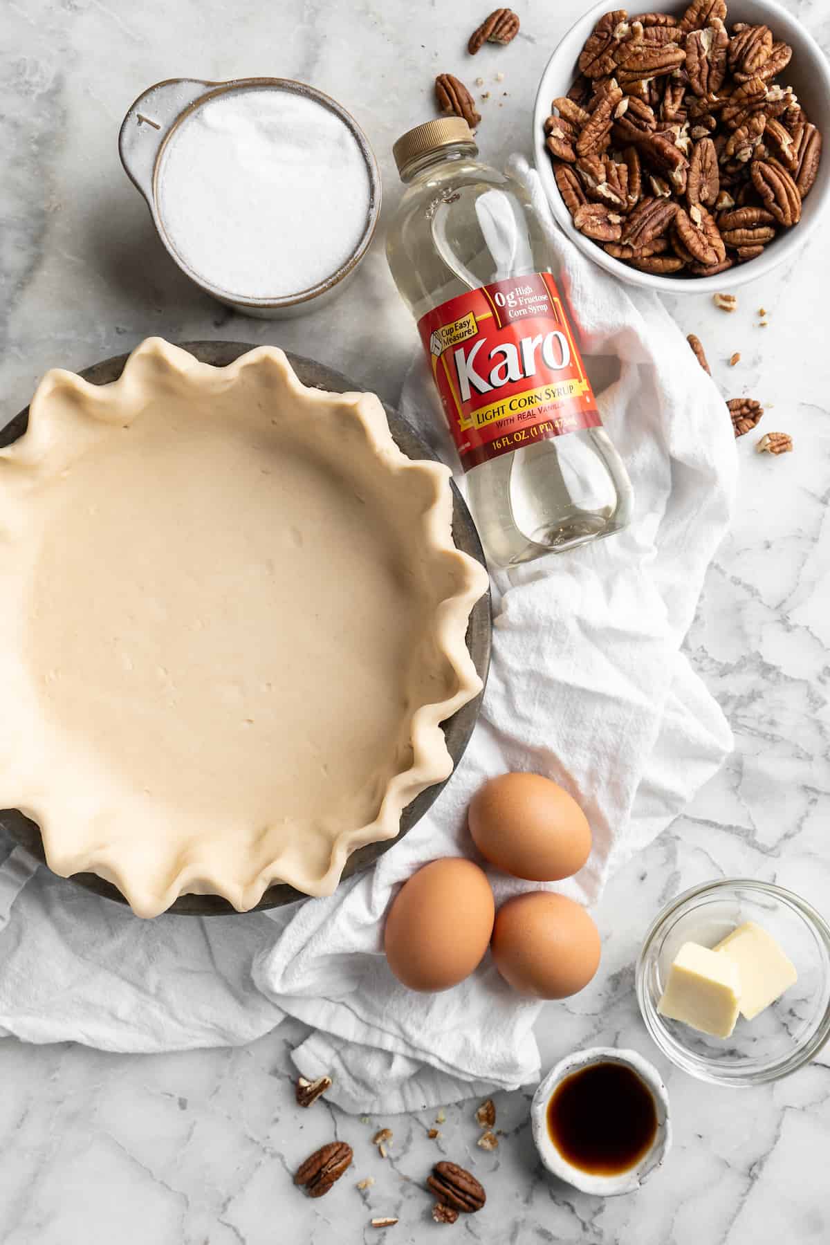 Ingredients to make pecan pie laid out on a white counter.