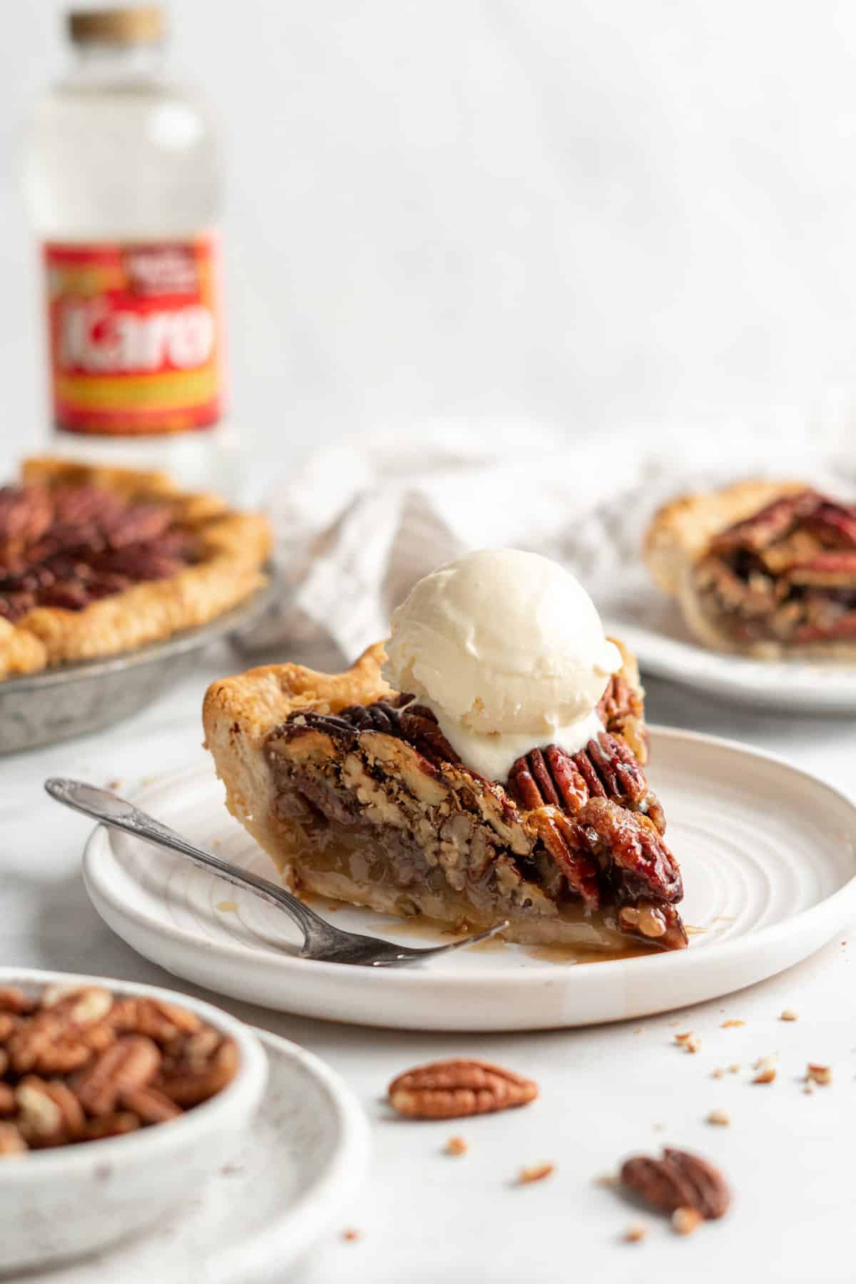 A scoop of vanilla ice cream melting over a slice of pecan pie.