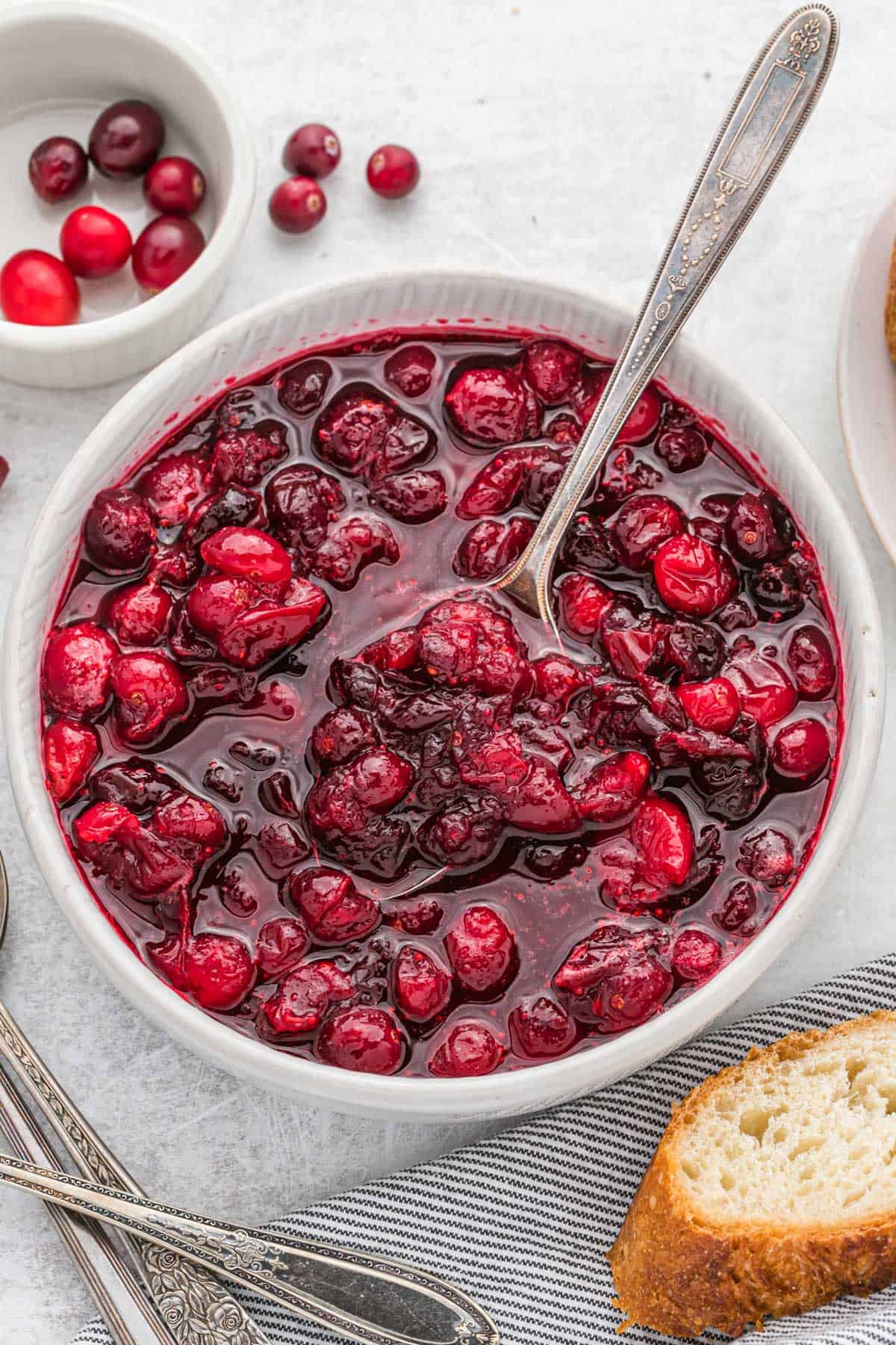 A whole of the best cranberry sauce with a silver spoon on a white countertop