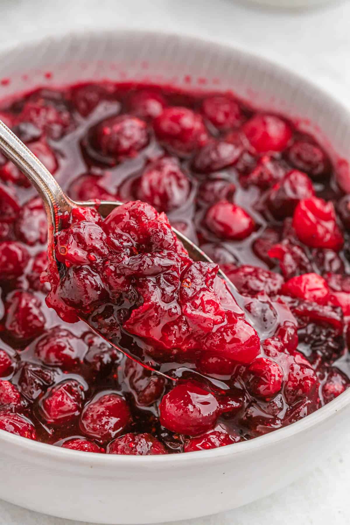 A spoon in a white bowl of homemade cranberry sauce.