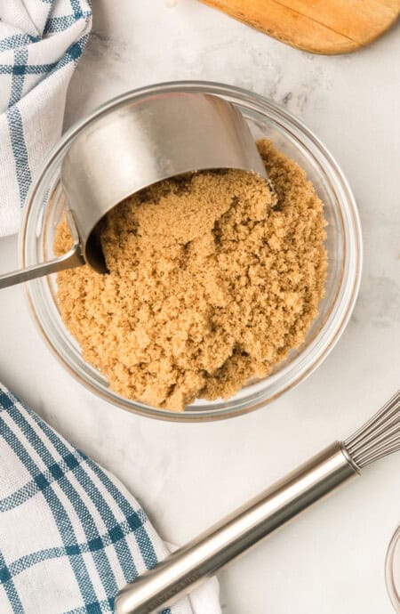 After learning how to make Brown sugar, it is being scooped into a measuring cup for baking