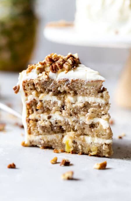 A lovely slice of a hummingbird cake recipe with pineapple cream cheese frosting and nuts ready to eat