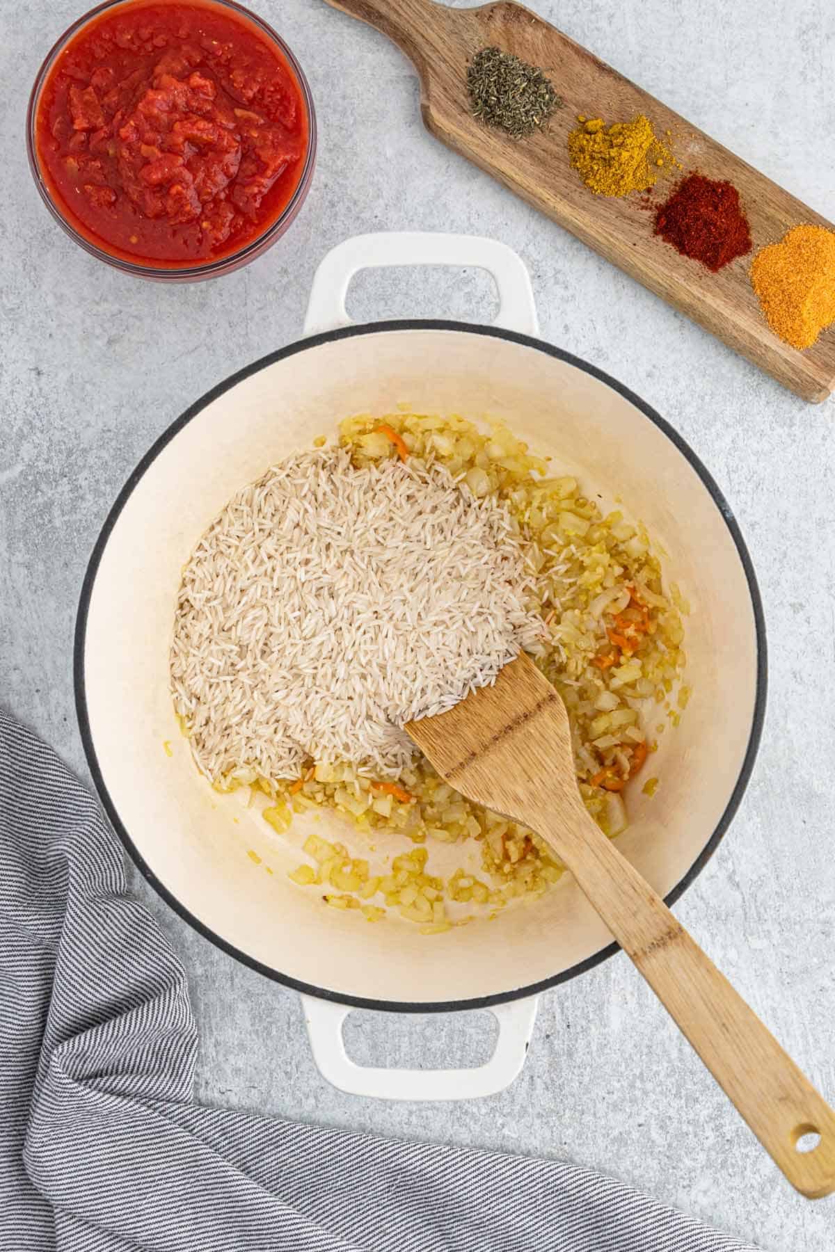 Adding rice to the cooked veggies in the pot.