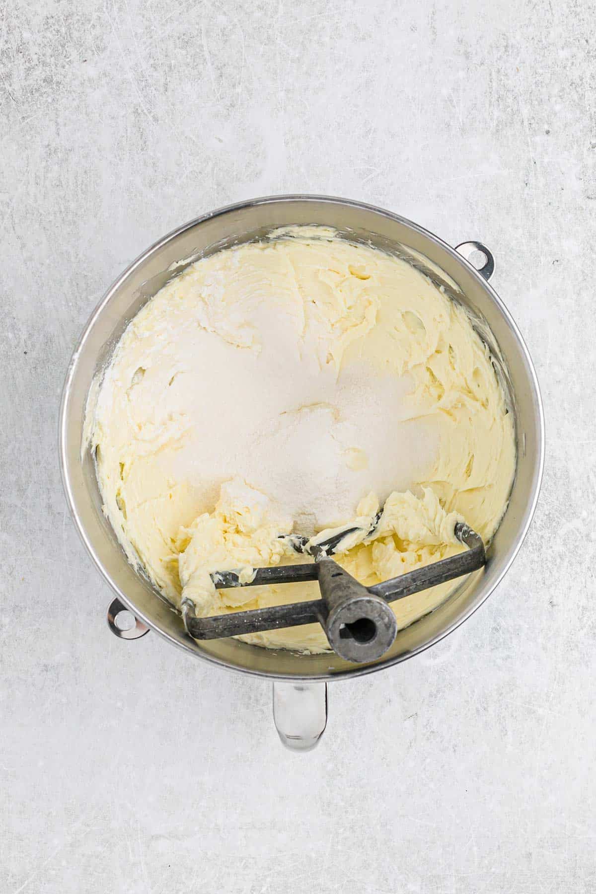 Sugar is added to the mixed butter and cream cheese mixture.