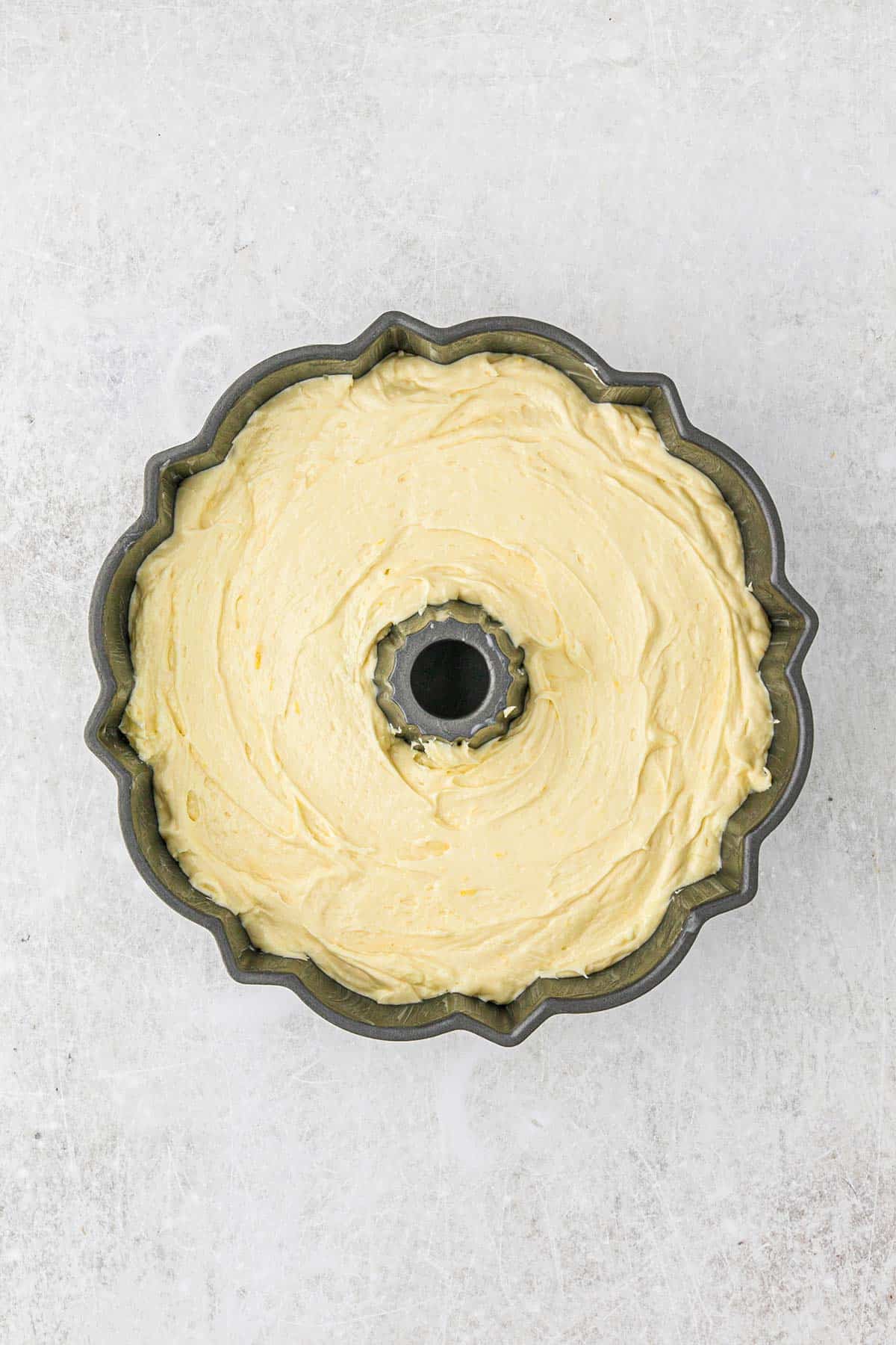 Batter added to the bundt cake pan on the table.