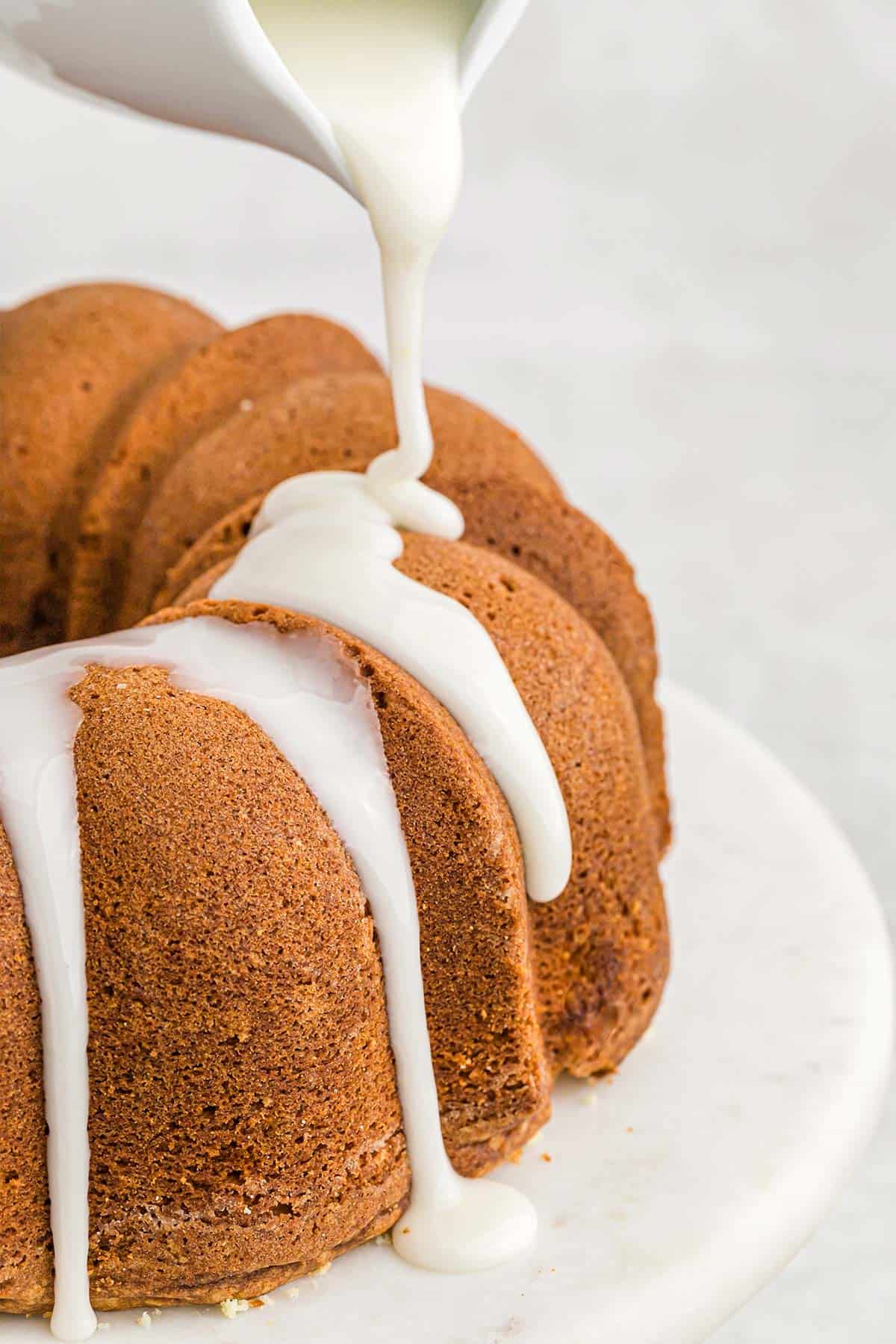 Drizzling lemon glaze over the baked cake.