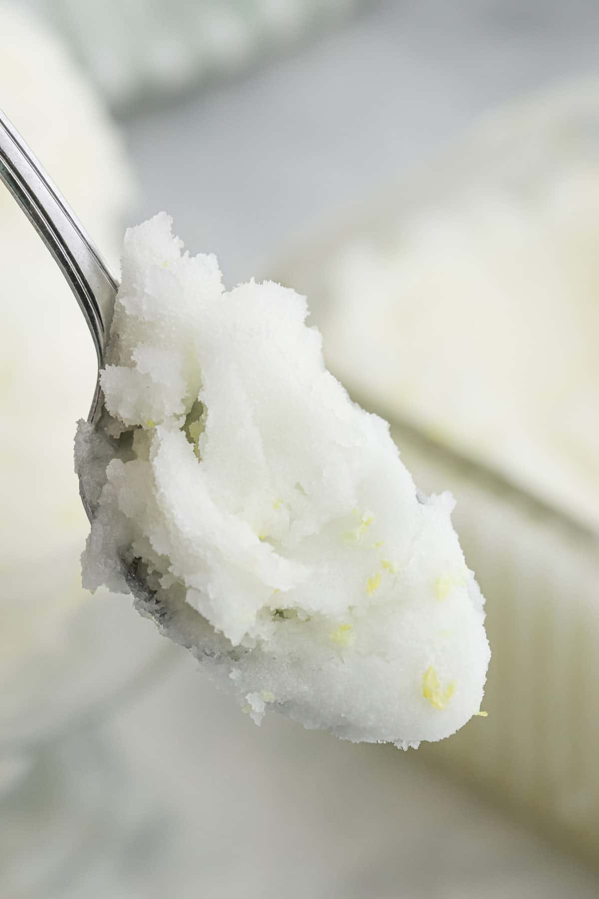 A spoonful of lemon sorbet with flecks of lemon zest in it.
