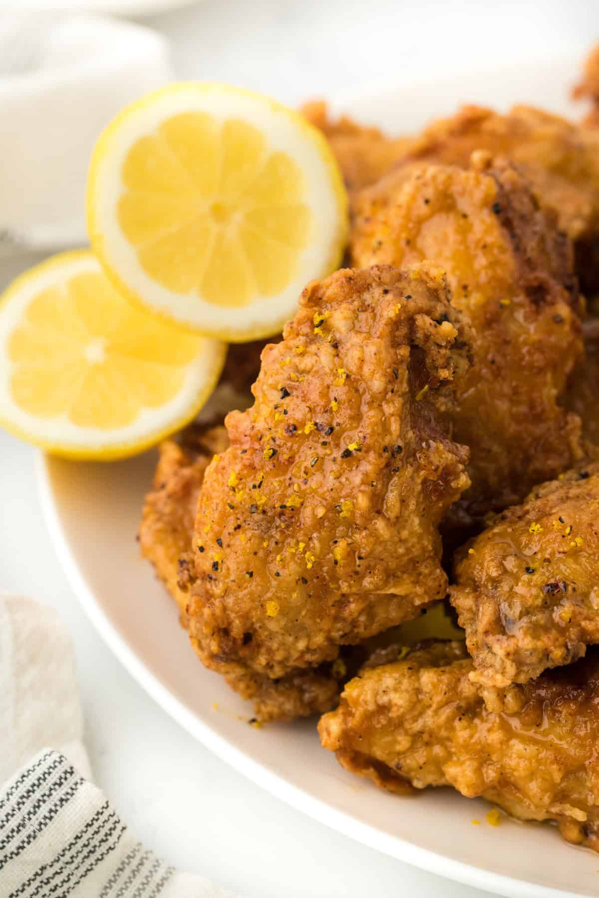 Lemon pepper chicken wings on a white plate with a sliced lemon