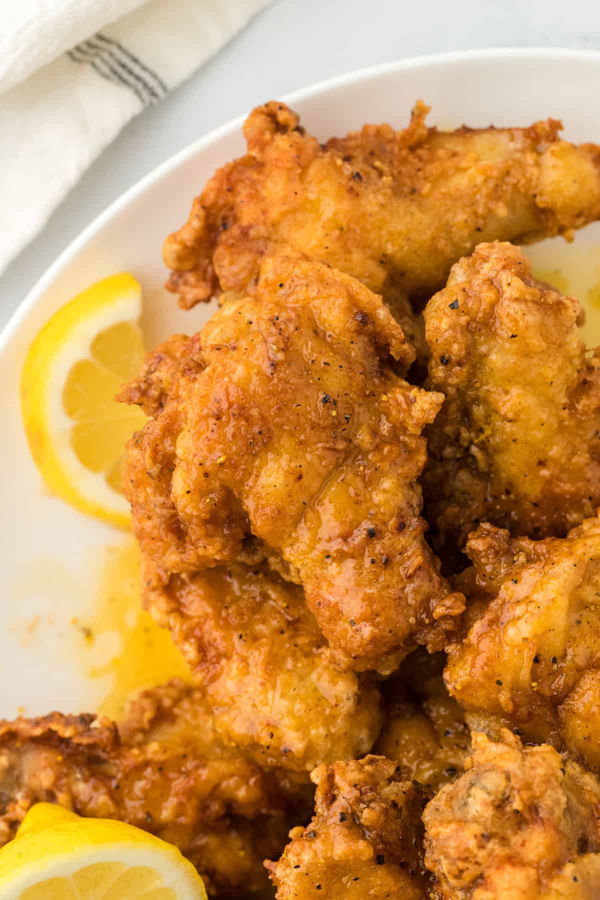lemon pepper wet wings on a white plate with sliced lemons ready to enjoy