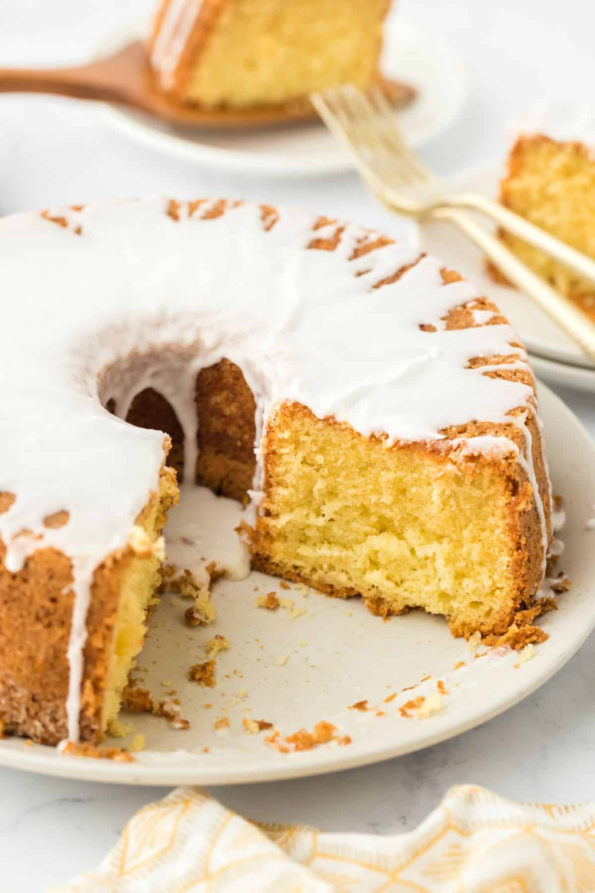 Louisiana Crunch Cake with slice missing on a white plate with more cake slices and forks in the background