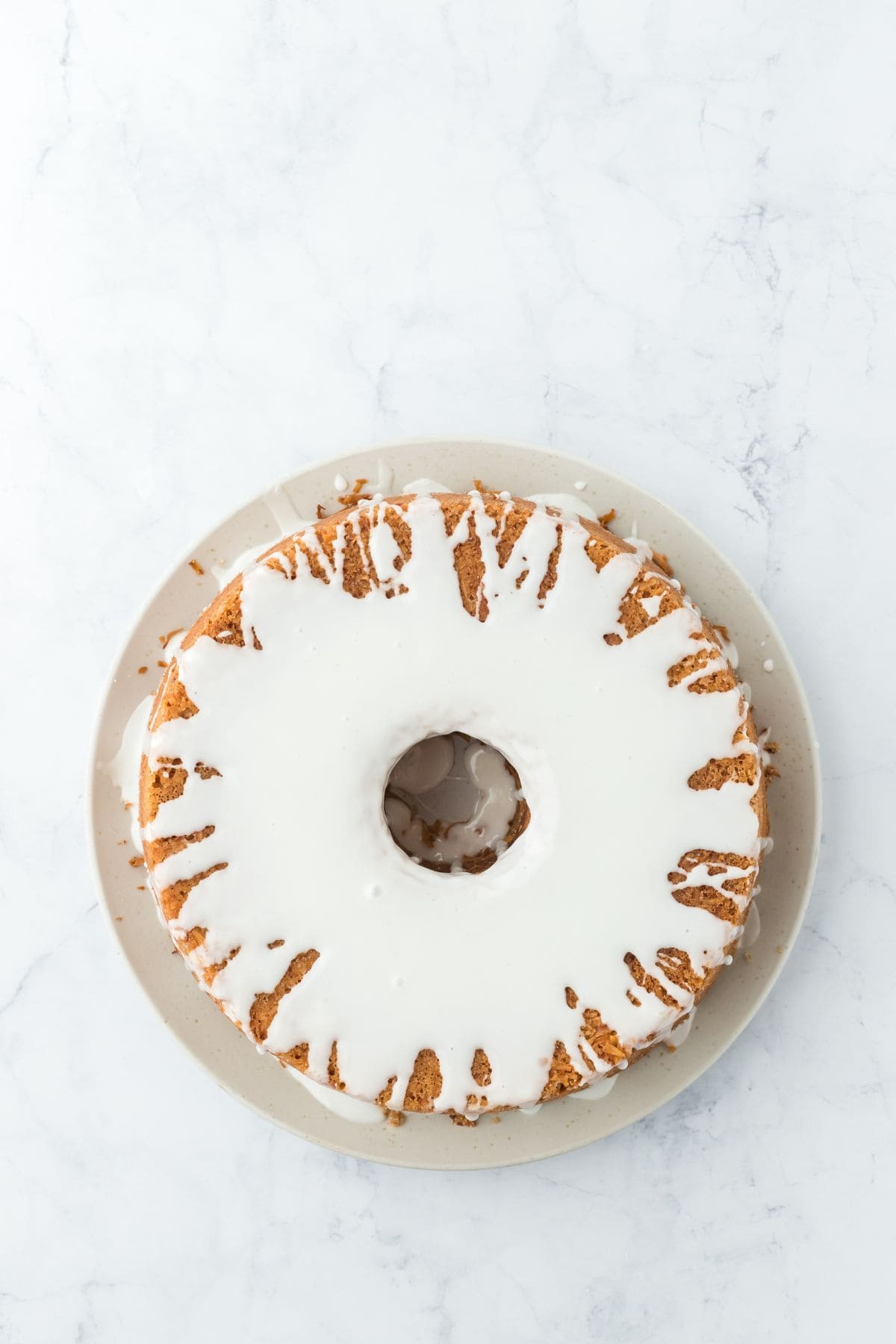 Overhead shot of Louisiana Crunch Cake with glaze poured over the top on a white plate