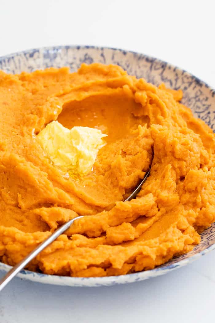 Classic and smooth mashed sweet potatoes with butter melting on it ready to serve