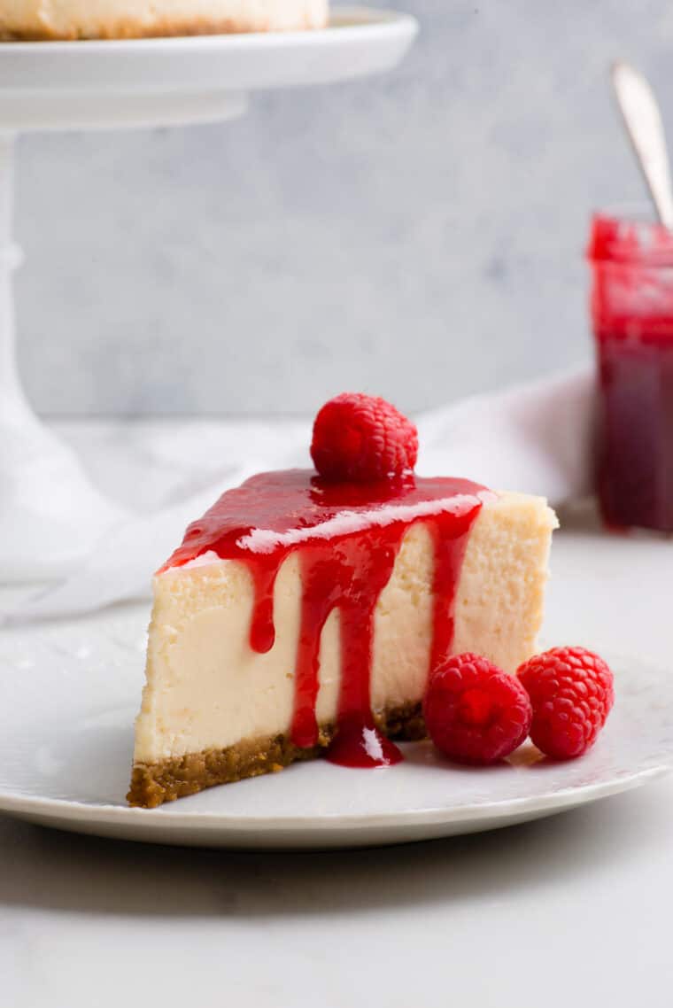 A slice of New York Cheesecake with raspberry sauce