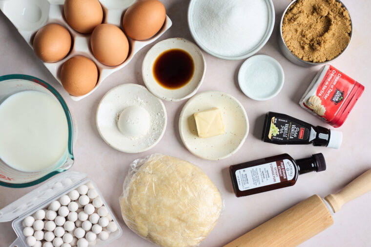 Pie dough, butter, eggs, vanilla, sugar and other ingredients to make a pie on a countertop