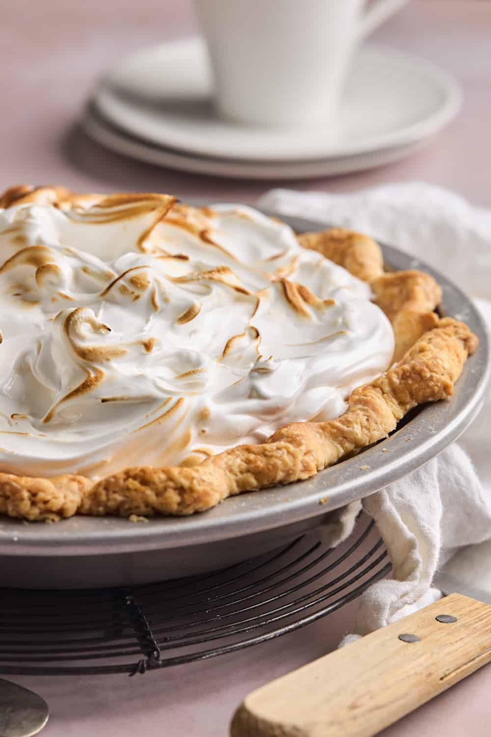 A meringue topped homemade butterscotch pie on a mauve countertop before serving