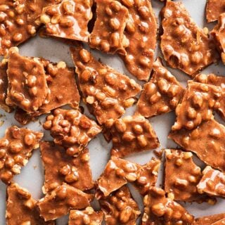 Broken peanut brittle against a white background