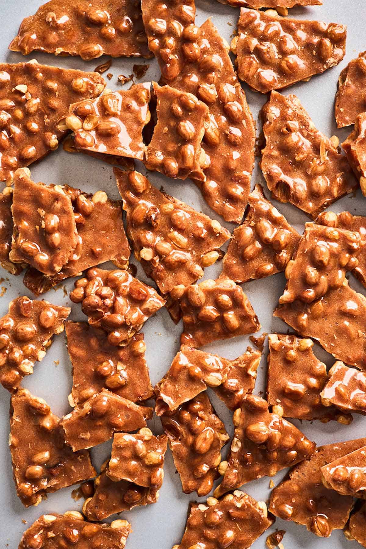 Broken peanut brittle against a white background