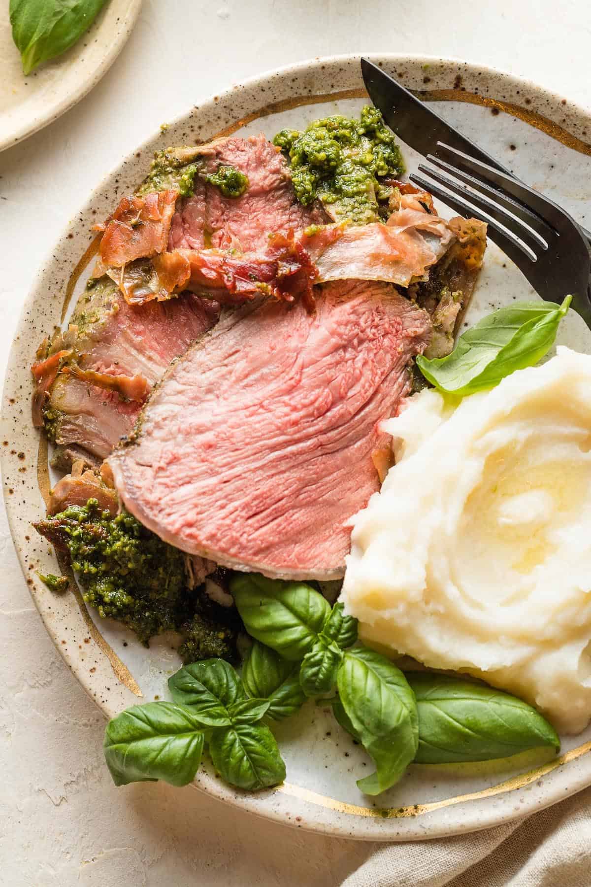 Beef roast and mashed potatoes on a stoneware plate.
