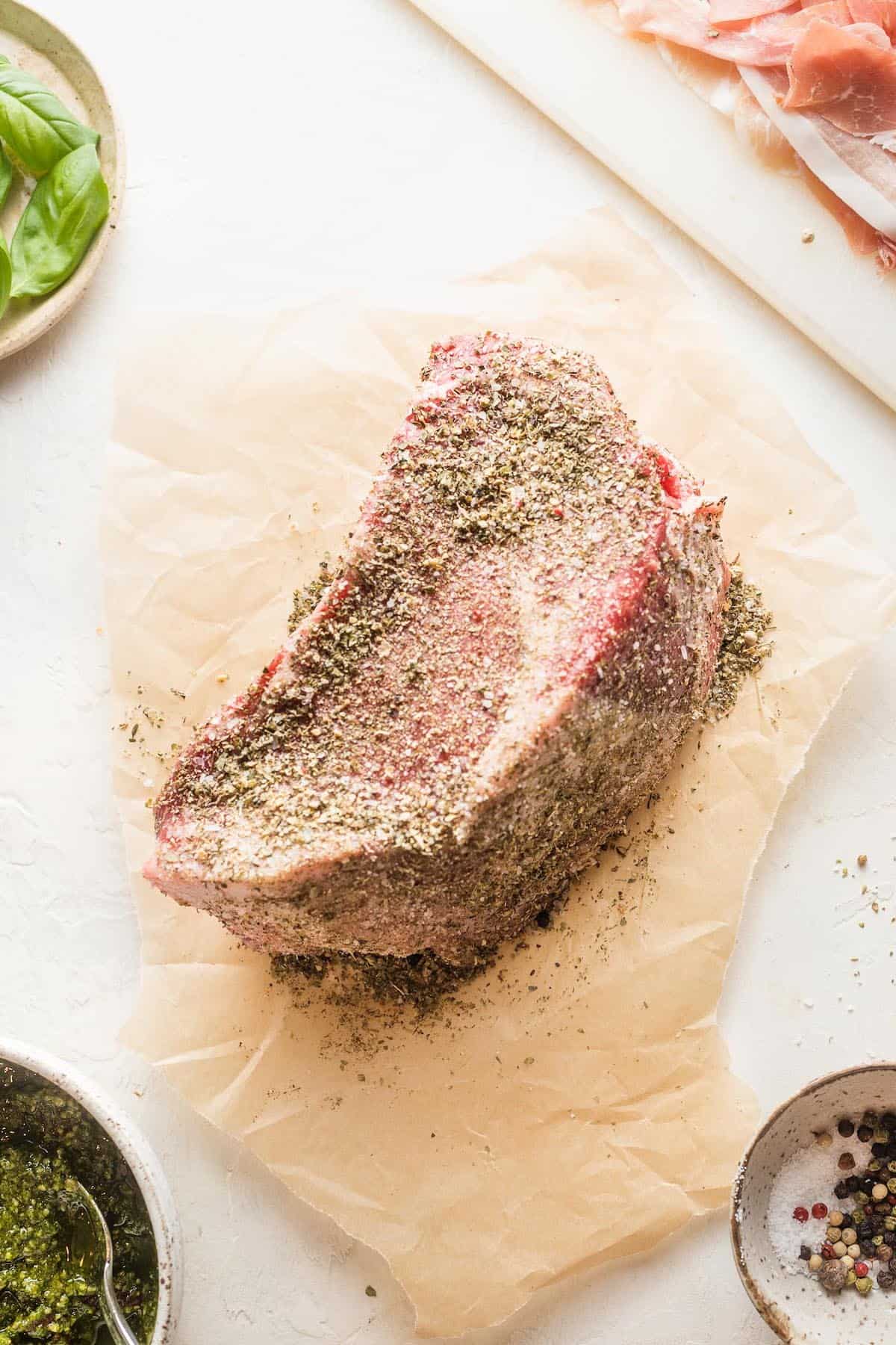Salt and pepper rubbed into a beef roast on a cutting board.