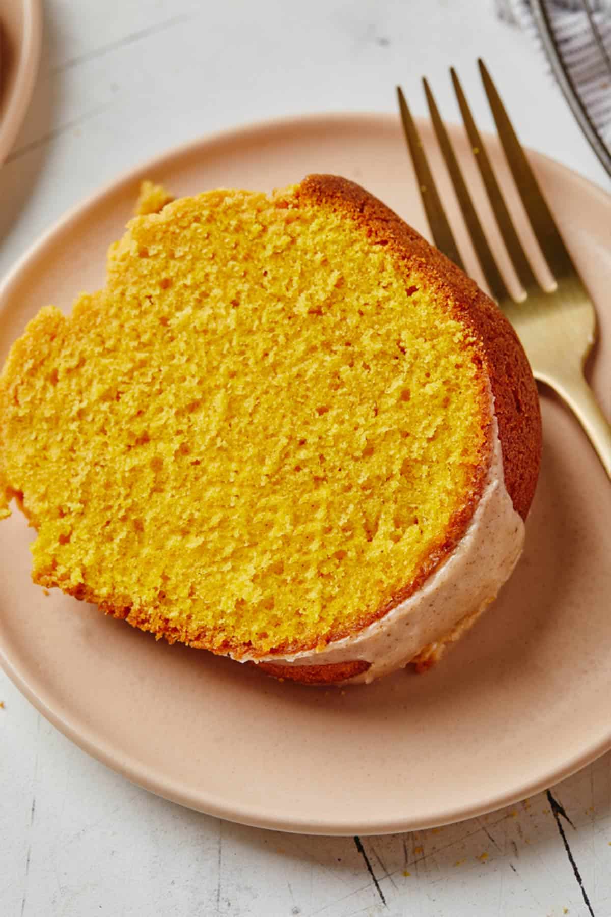 Closeup of a slice of pumpkin pound cake with glaze on a plate with a fork.