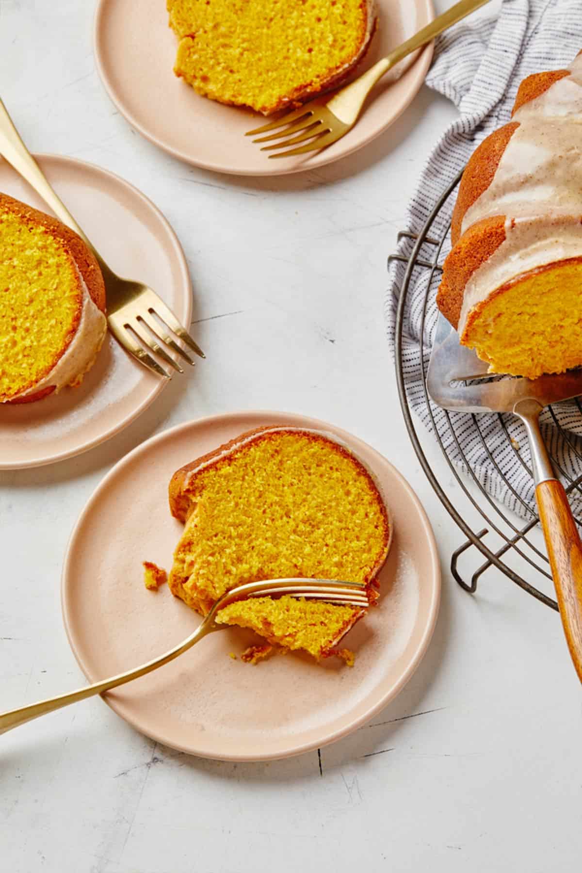 Pumpkin spice bundt cake recipe sliced on plates with forks on the white table.