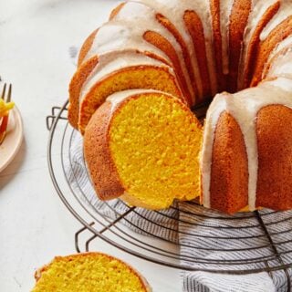 A pumpkin bundt cake on a wire rack with slices cut and pulled out of the cake.