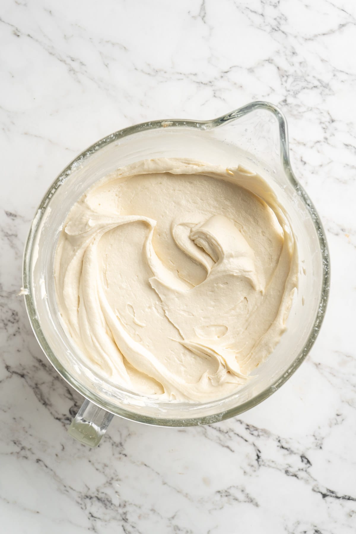 Fully mixed batter for the white chocolate raspberry bundt cake on a glass measuring jar