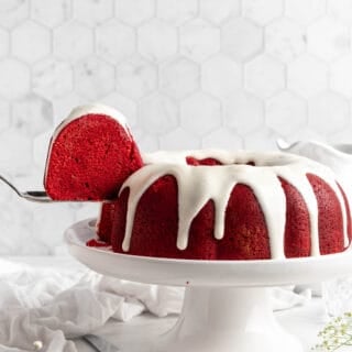 red velvet bundt cake on a cake pedestal with a slice taken out